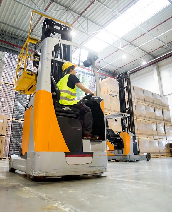 Forklift operator during work in large warehouse
